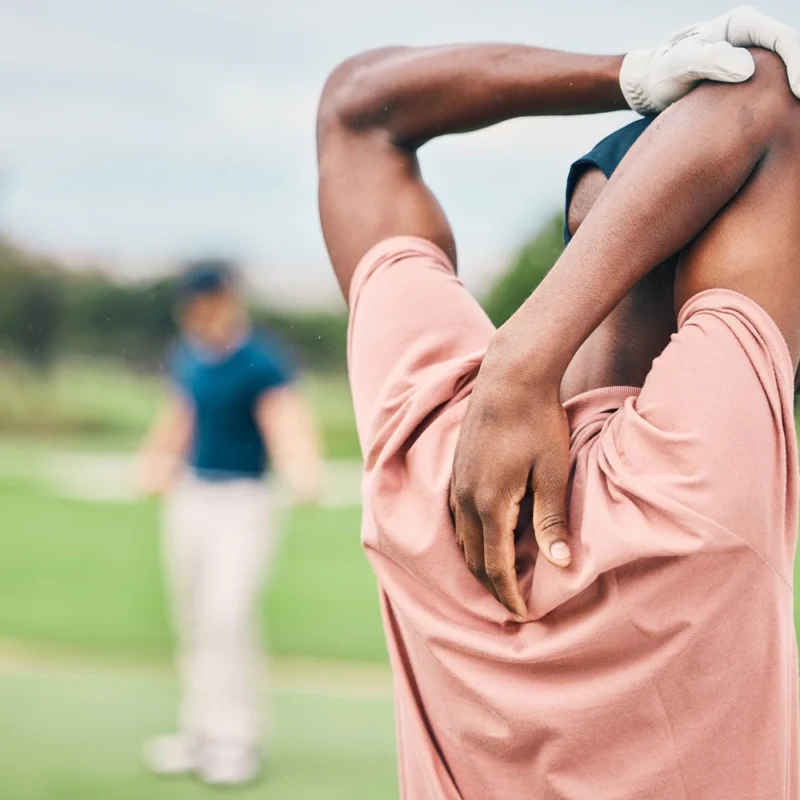 Golf player stretching arms on course for game, practice and training for competition.