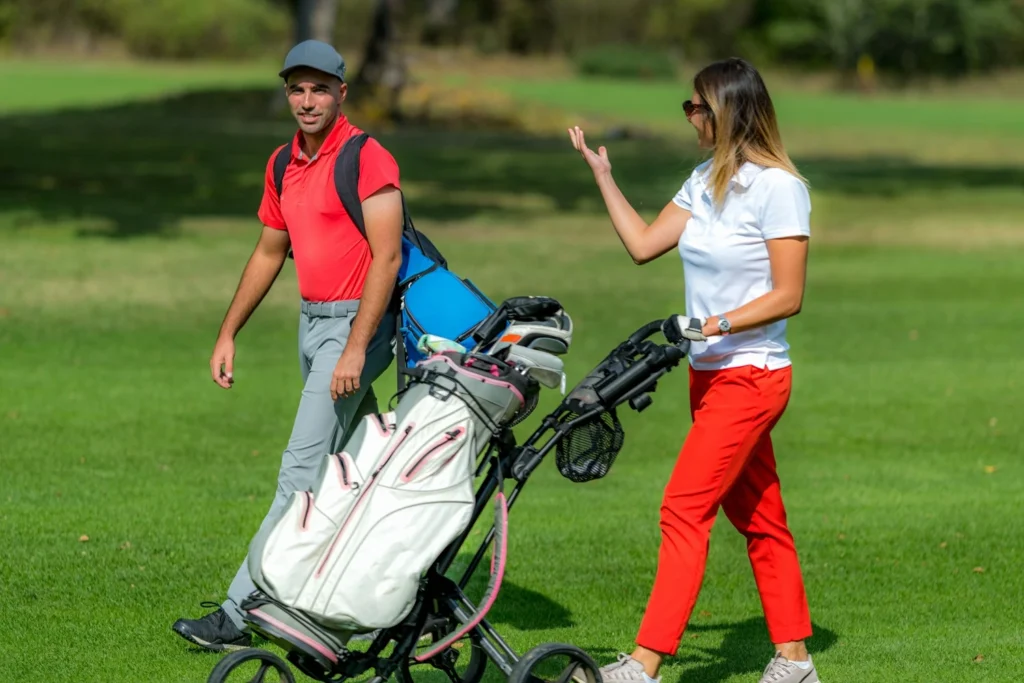 Young couple enjoying a game of golf, walking the fairway on a n Irish golf course on a beautiful sunny day