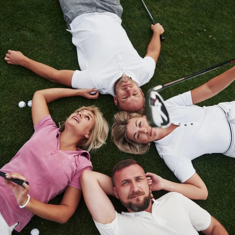 Four golf players lie on the golf course and relax after the game.