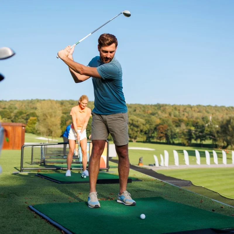 Young Pair learning how to play golf on a driving range