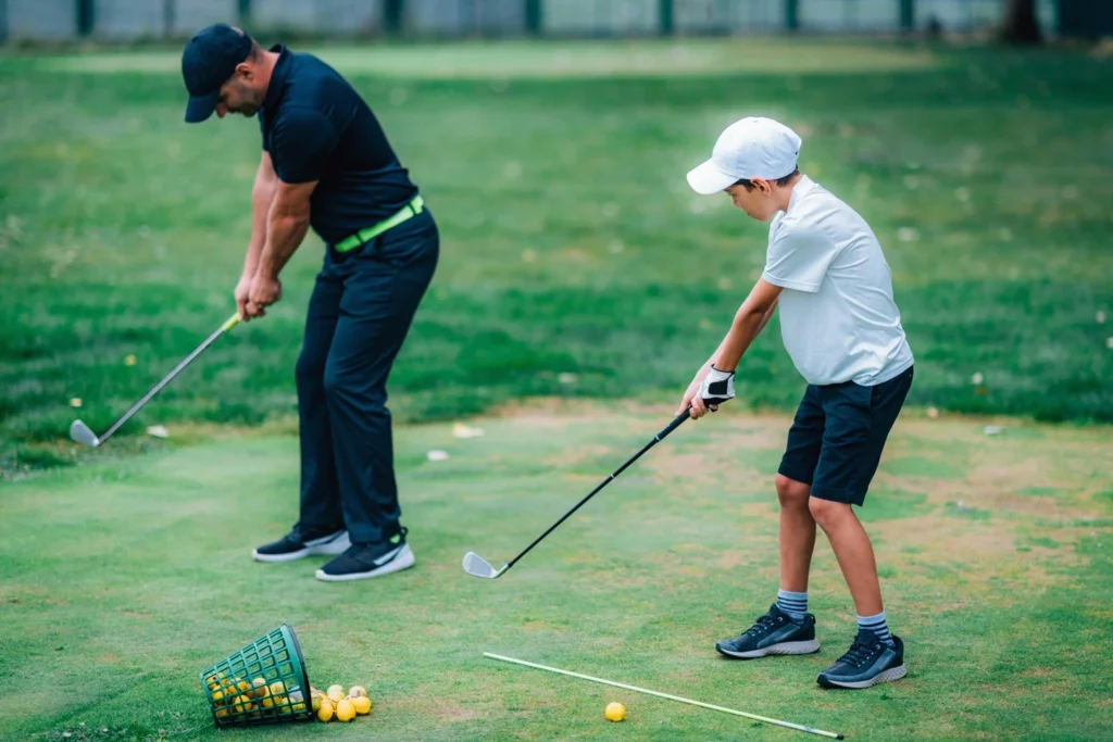 A golf Instructor and a junior golf player practicing on a Golf Practice Range