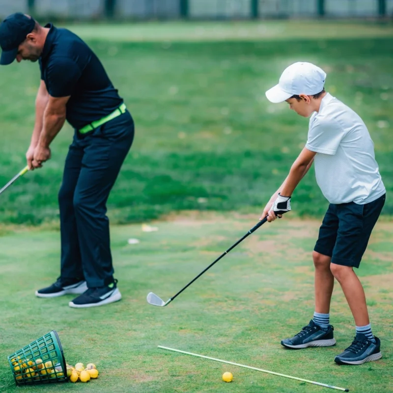 A golf Instructor and a junior golf player practicing on a Golf Practice Range