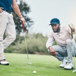 Two golfers assess a putt on the green, demonstrating smart decision-making and course management strategy during a round.