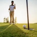 Golf ball inches from the hole as a golfer celebrates in the background, highlighting the confidence and precision possible with the LAB Mezz.1 Max putter.