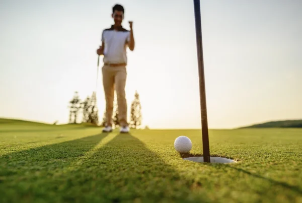 Golf ball inches from the hole as a golfer celebrates in the background, highlighting the confidence and precision possible with the LAB Mezz.1 Max putter.